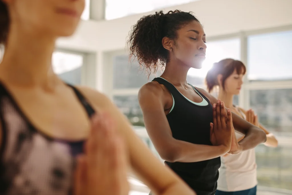 students in Anjali Mudra, getting ready for a hatha yoga asana class
